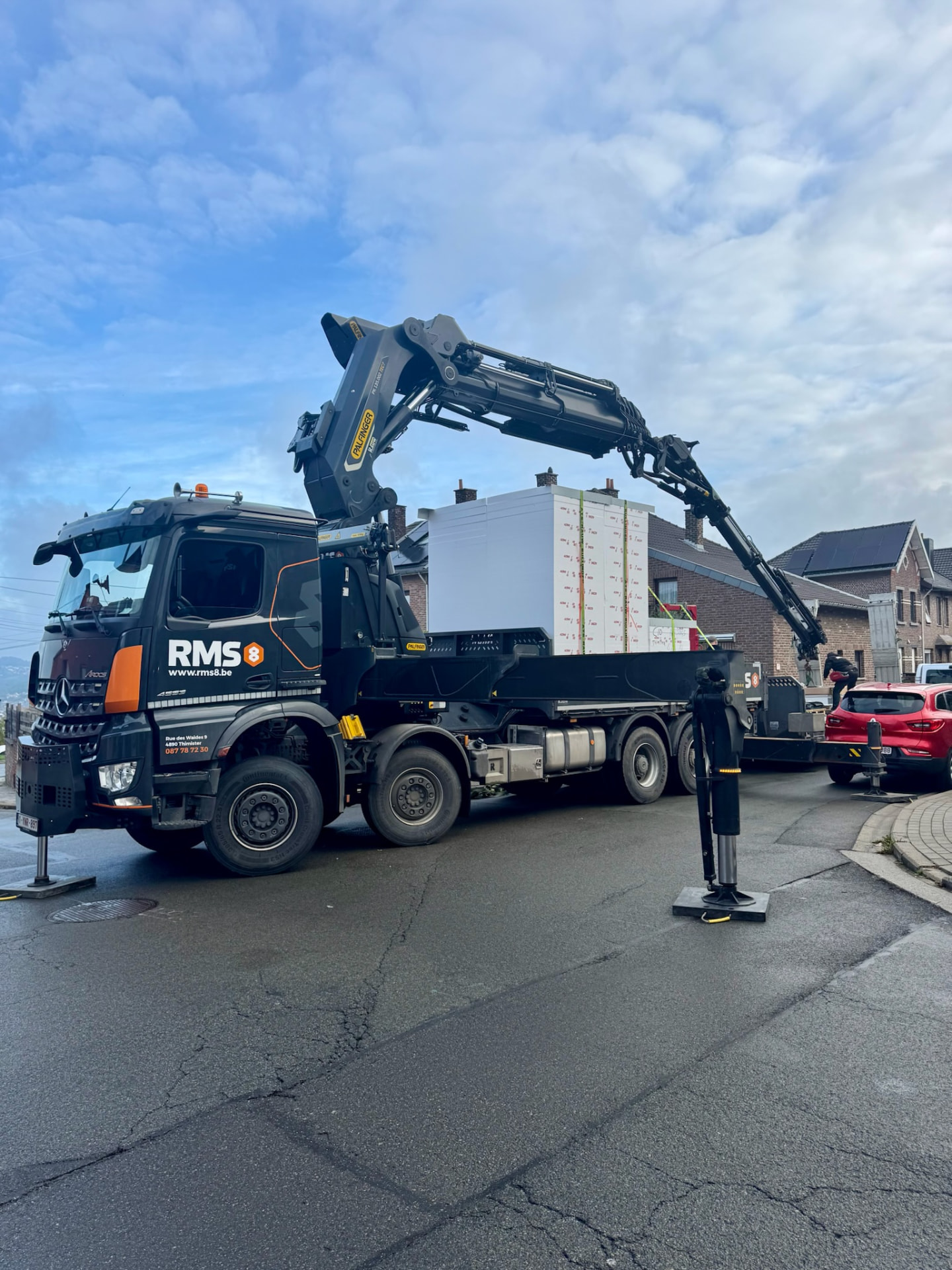 Camion-grue RMS8 chargé de panneaux, en cours de livraison dans une rue